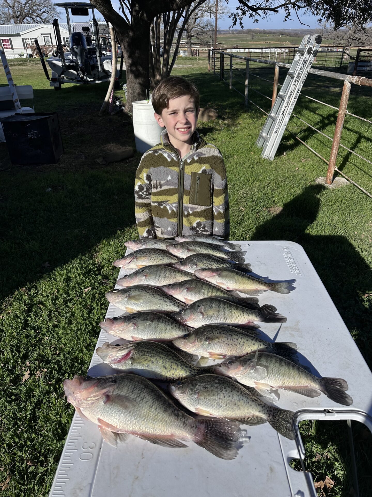 a young boy standing next to a table filled with fish